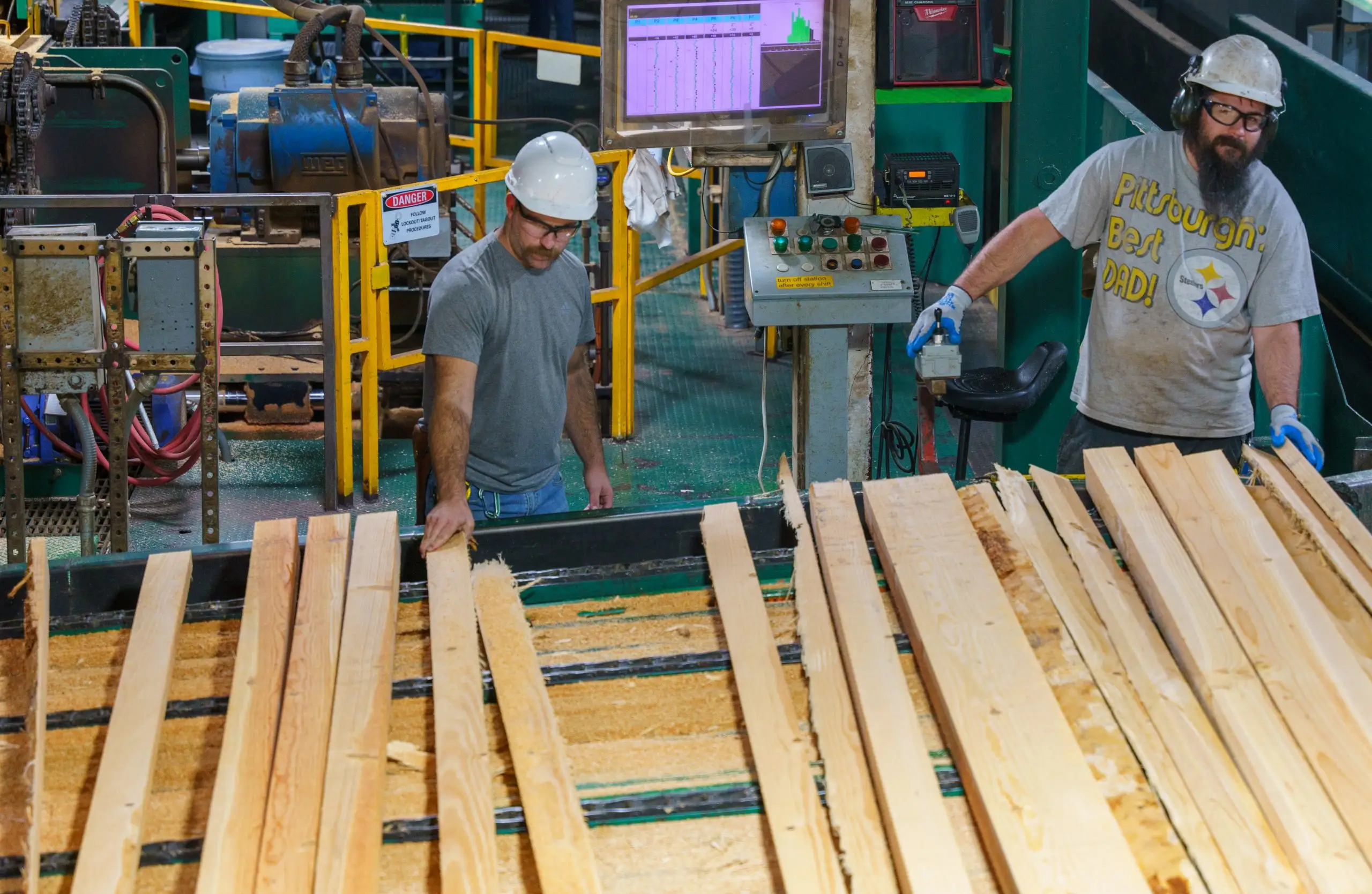 Two graders working boards along the green chain beneath a grade readout.